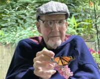 Man holding butterfly in lush garden setting