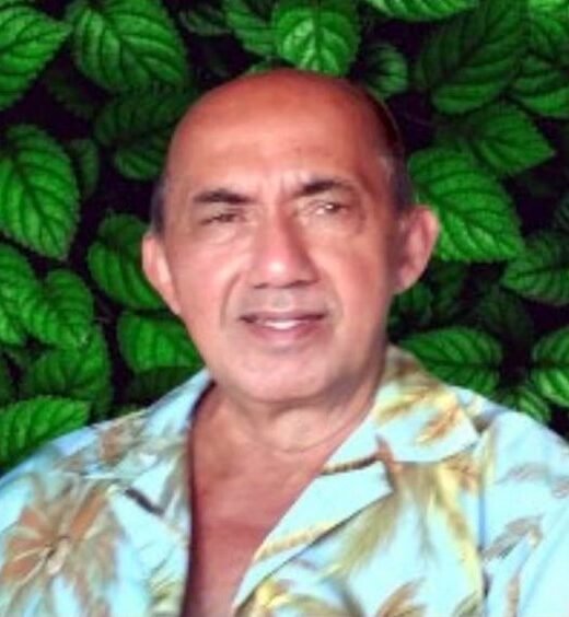 Smiling man against leafy background.