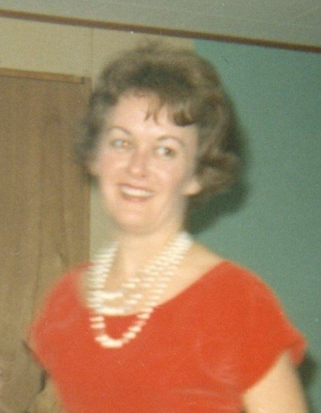Woman smiling in red dress with pearl necklace.