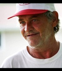 Man wearing red and white cap, smiling outside.