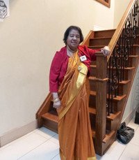 Woman in sari standing near staircase.