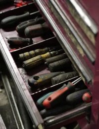 Open toolbox drawer with various hand tools inside.