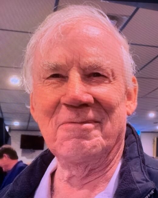 Smiling elderly man indoors with jacket.