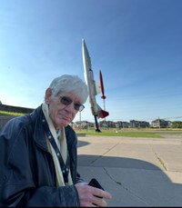 Man outside near a tilted aircraft display.