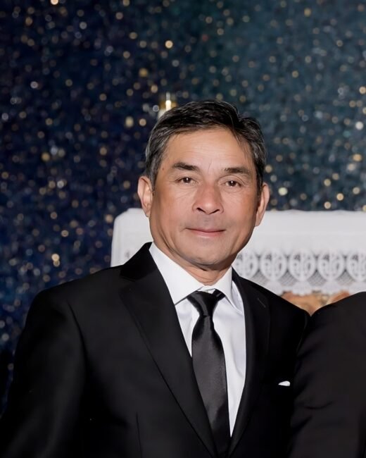 Man in black suit with a dark background.