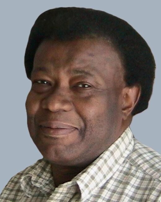 Smiling man in checkered shirt against gray background.