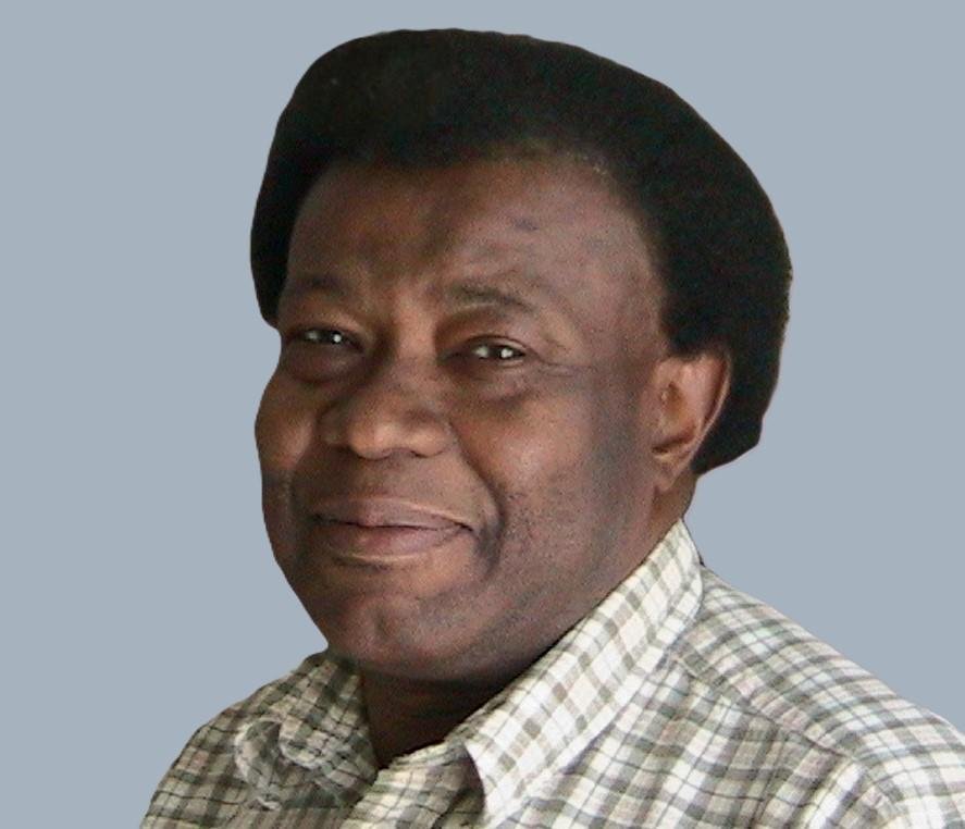 Smiling man in checkered shirt against gray background.