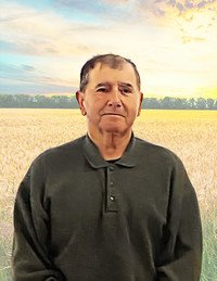 Man standing in front of wheat field at sunrise.