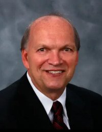 Smiling man in suit with gray background.