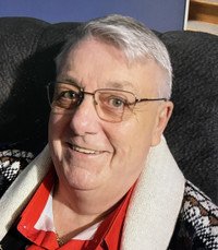 Smiling person with glasses and sweater.