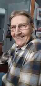 Smiling person wearing glasses and plaid shirt indoors.