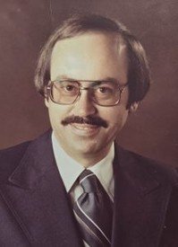 Man with glasses and mustache in suit portrait.