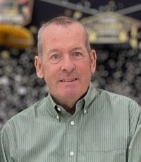 Man in green shirt smiling indoors.