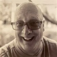 Smiling person wearing glasses in sepia photograph.