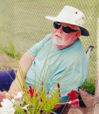Man in hat sitting outside by flowers