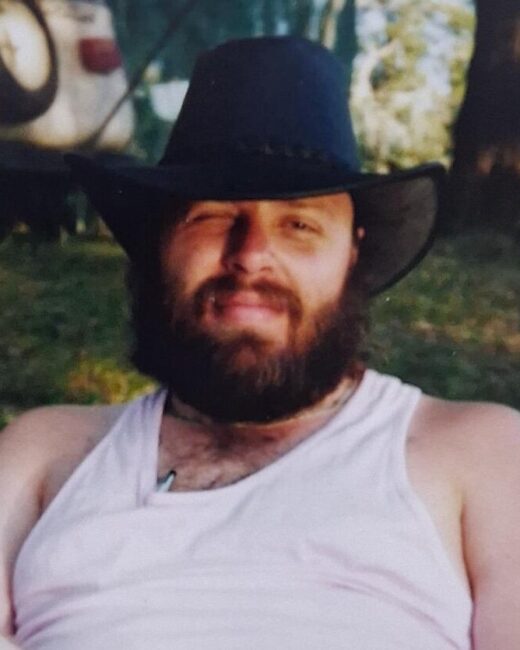 Bearded man in hat smiling outdoors