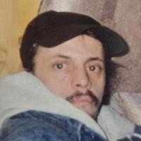 Man wearing a cap, seated indoors.