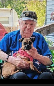 Elderly man holding a small dog on lap.