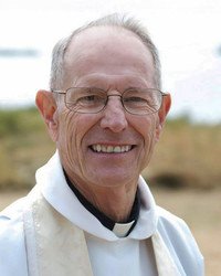 Smiling elderly man in religious attire outdoors.