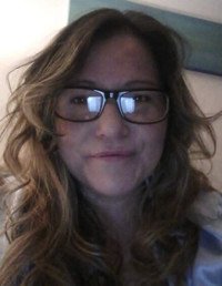 Person wearing glasses and smiling indoors.