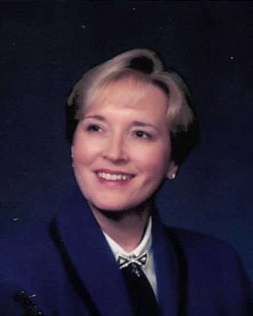 Woman smiling in professional attire, dark background.