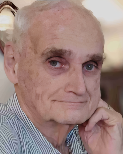 Elderly man with striped shirt smiling gently.