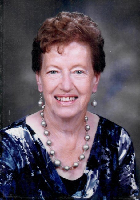 Smiling woman wearing necklace and blouse.