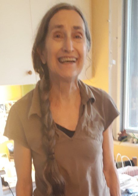 Woman smiling indoors with a braid hairstyle.