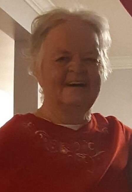 Smiling elderly person in a red shirt indoors.