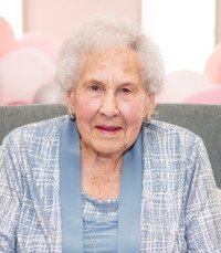 Elderly woman smiling in blue outfit.