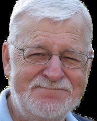 Elderly man with white beard and glasses smiling.