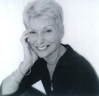 Smiling elderly woman posed with hand on cheek.