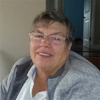 Smiling person wearing glasses and gray sweater