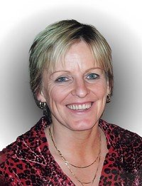Smiling person with short blond hair and red shirt.