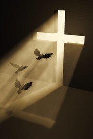 Lighted cross and flying doves in shadow.