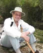 Man hiking outdoors with walking stick and hat
