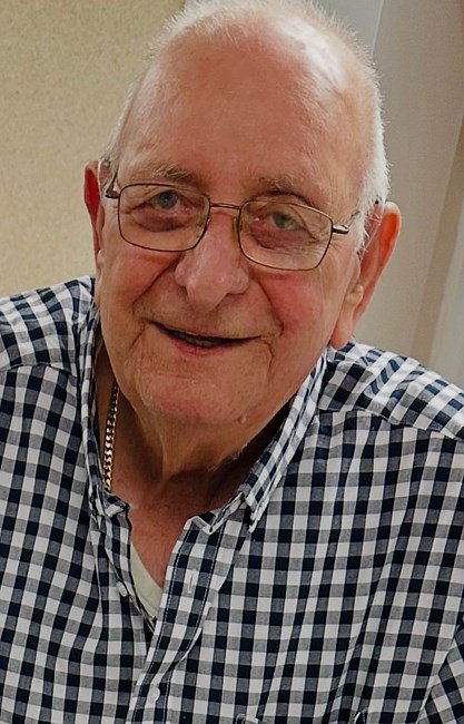 Smiling elderly man in a checkered shirt.