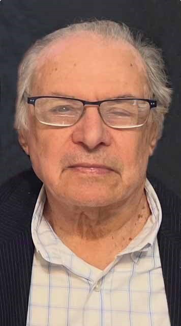 Elderly man wearing glasses and a checkered shirt.