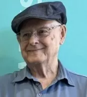 Elderly man wearing a cap and glasses smiling.