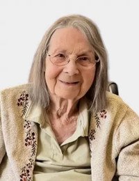 Elderly woman smiling in floral cardigan.