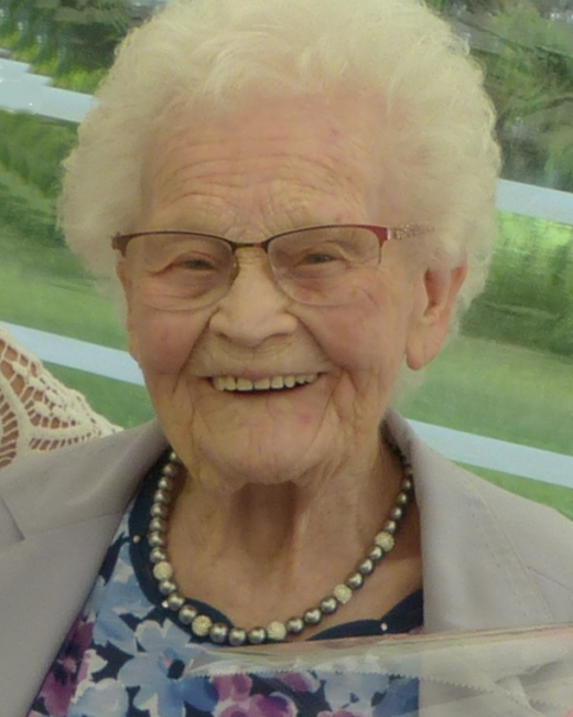 Elderly woman smiling outdoors with floral dress.