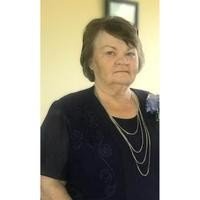 Elderly woman in dark dress with necklace.