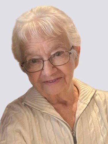Elderly woman wearing glasses and a beige sweater.