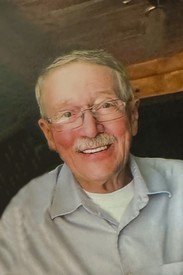 Smiling elderly man wearing glasses and a shirt.