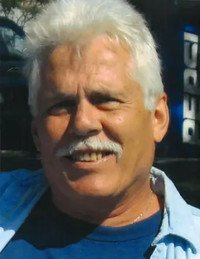 Smiling man with white hair and mustache outdoors.