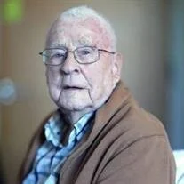 Elderly man with glasses sitting indoors