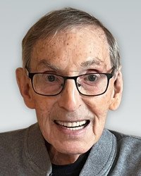 Smiling elderly man wearing glasses and gray sweater.