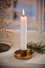 Lit white candle in gold holder on windowsill