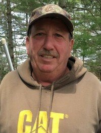 Man in CAT hoodie and camo cap outdoors