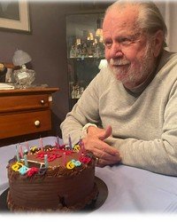Older man smiling with birthday cake and candles.